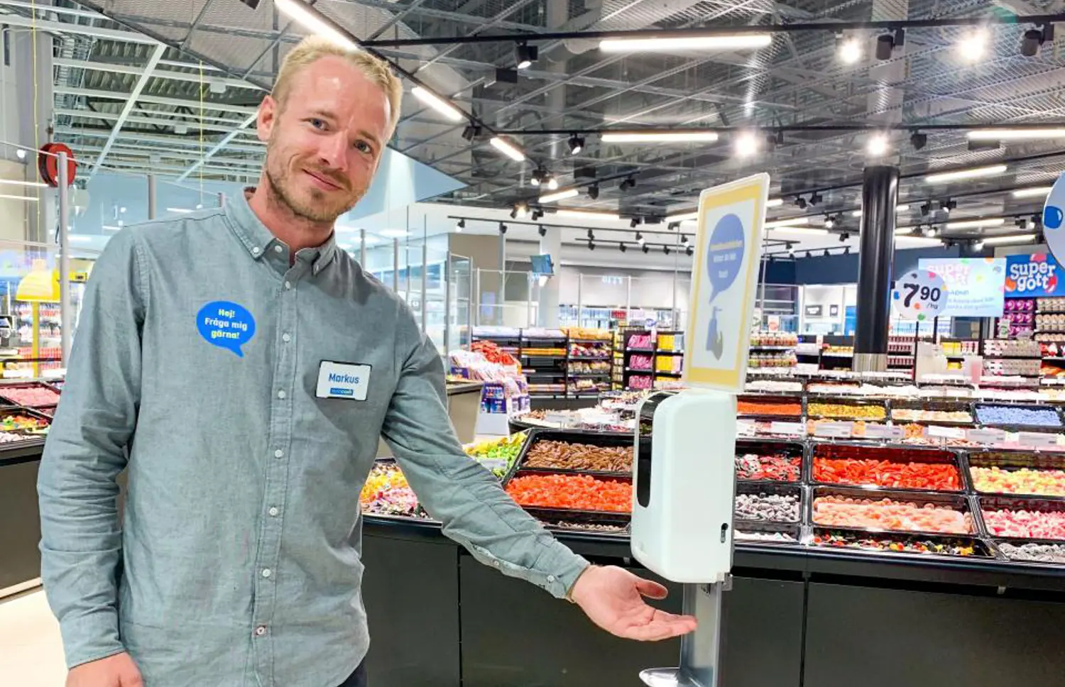 Butiksanställd står vid handspritsautomat